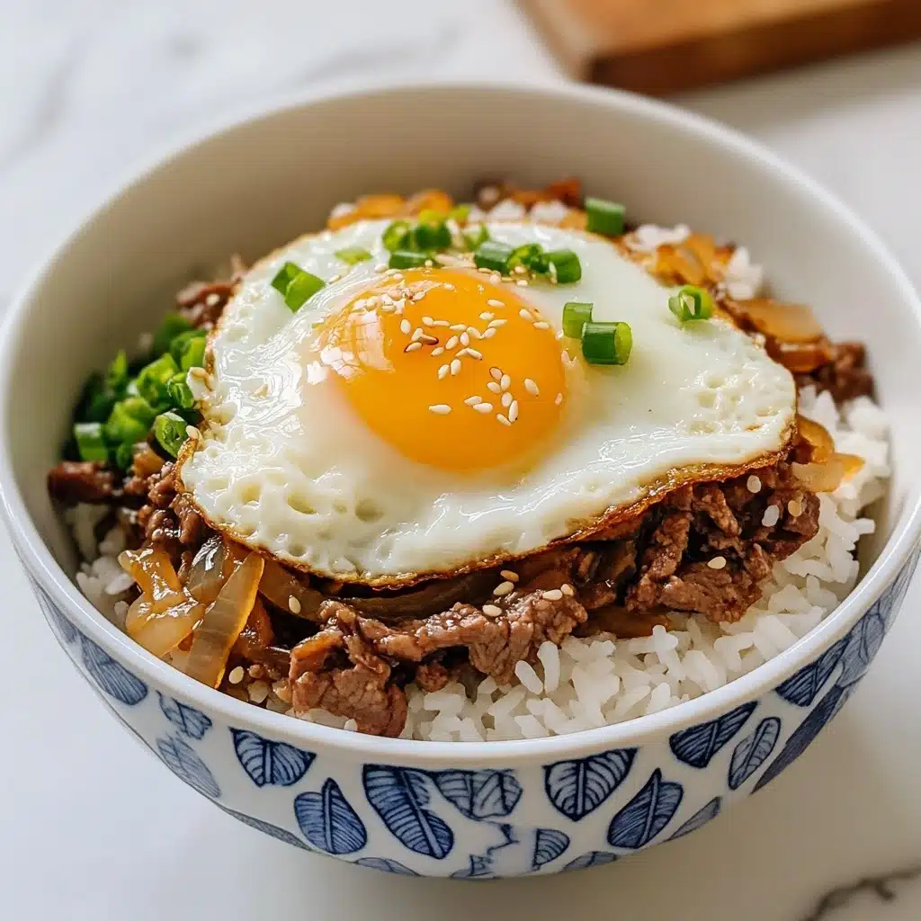 Gyudon Japanese Beef & Rice Bowls, Japanese Gyudon Recipe, Quick Gyudon Meal, Authentic Gyudon, Japanese Beef Rice Bowl A white bowl with blue leaf patterns holds a dish with three main layers. The bottom layer is white, steaming rice with a slightly fluffy texture. On top of the rice is a layer of brown cooked beef mixed with sautéed translucent onions and sliced green onions adding green hints. The top layer is a sunny-side-up egg with a bright yellow yolk spilling gently over the beef, and white egg edges slightly crisped. Light sesame seeds sprinkle over the egg and beef. The bowl is placed on a white marbled surface.