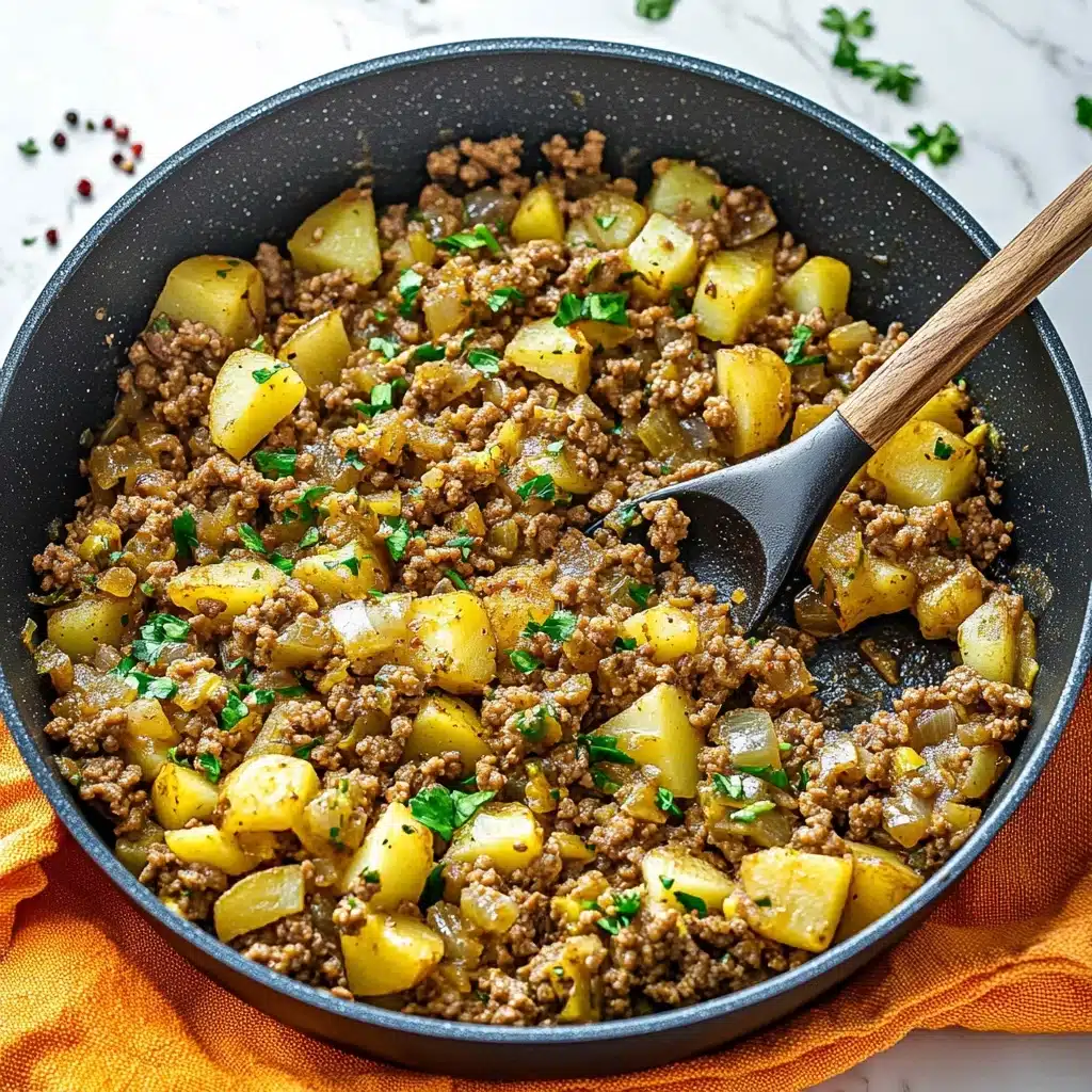 Mexican Picadillo, Mexican Picadillo recipe, easy Mexican dishes, hearty weeknight dinner, flavorful Mexican ground beef A dark gray cooking pan filled with a cooked mixture of small, light brown ground meat pieces and yellowish diced potatoes, mixed with bits of green herbs and small pieces of cooked onions and peppers, creating a varied texture. Some bright green chopped parsley is sprinkled on top. A black spoon with a wooden handle is scooping some of the food on the right side of the pan. The pan is placed on a folded orange and yellow cloth, and the background is a white marbled surface with scattered red pepper flakes.