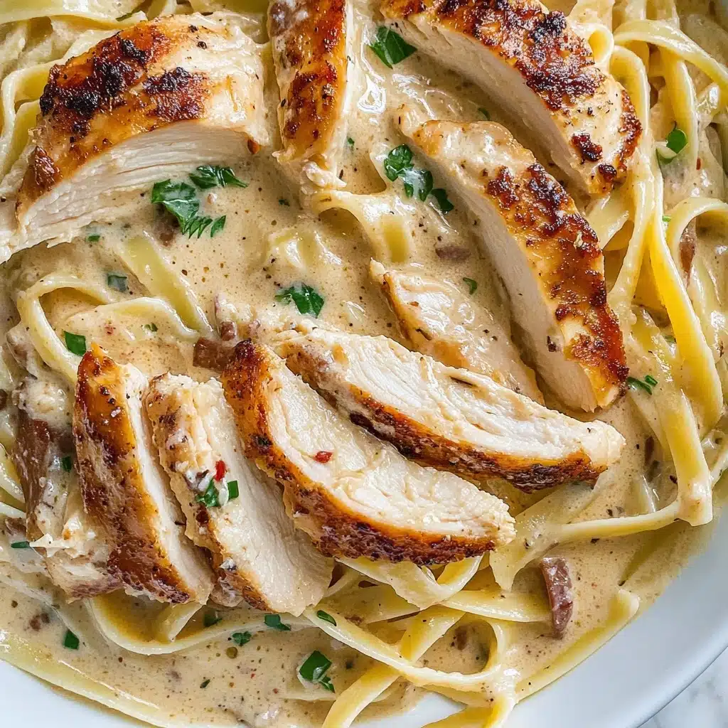 Creamy Cajun Chicken Pasta, Cajun Chicken Pasta, Creamy Pasta Recipes, Spicy Chicken Pasta, Easy Cajun Pasta The image shows a close-up of creamy pasta with several slices of browned chicken on top. The pasta is long and flat, coated in a thick light beige sauce with small red bits, suggesting a rich, creamy texture. Scattered on the pasta are small green herb pieces and thin white curls of cheese, adding color contrast. The chicken slices are placed around the pasta, showing a well-cooked, slightly crispy outside, and juicy inside. The meal is presented in a white bowl, sitting on a white marbled surface.
