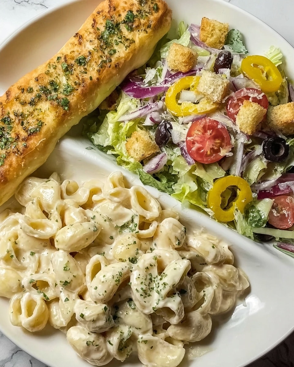 A white plate with three sections of food is shown on a white marbled surface. The bottom left section has creamy pasta with small, curved shapes coated in white sauce with green herb sprinkles. The top right section holds a fresh salad with green lettuce, yellow pepper rings, sliced red onions, small black olives, diced red tomatoes, and golden brown croutons, all lightly sprinkled with grated cheese. The top left section has a golden brown breadstick with a soft texture sprinkled with green herbs. Photo taken with an iphone --ar 4:5 --v 7