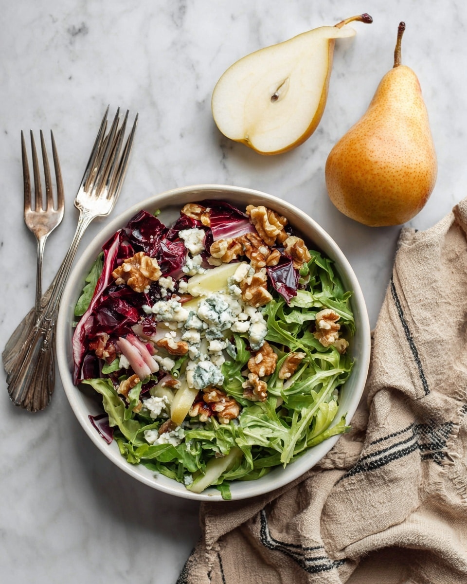 A white bowl filled with a layered salad on a white marbled surface: the bottom layer is bright green arugula leaves mixed with dark red radicchio pieces, topped with white and blue chunks of blue cheese, small light brown walnut pieces, and two peeled pear halves with smooth light beige flesh leaning against the side. Next to the bowl, there are two silver forks and a whole brown pear with two pale yellow pear slices showing inside. A crumpled beige cloth with thin black stripes is on the right side of the bowl. Photo taken with an iphone --ar 4:5 --v 7