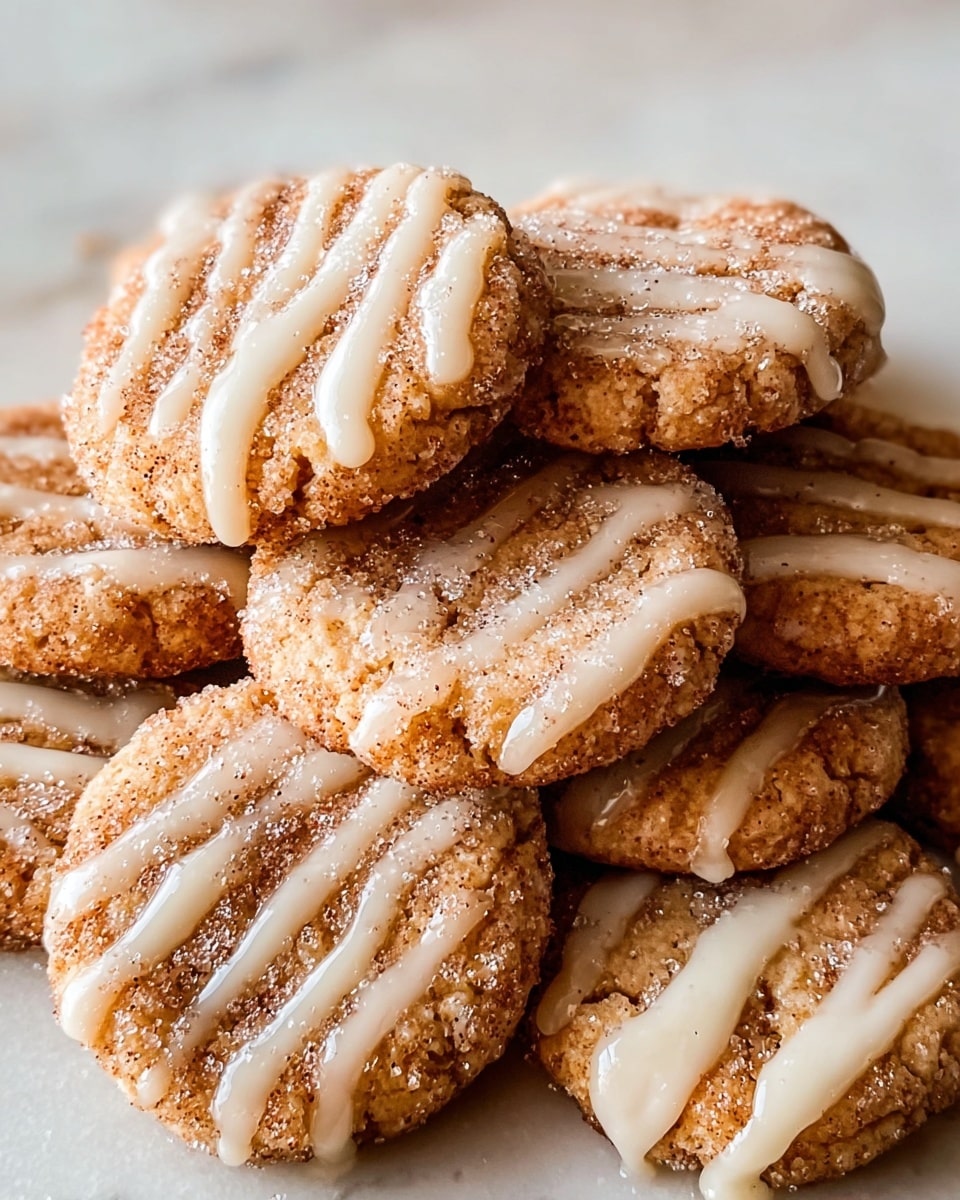 A close-up view of several round cookies stacked on each other on a white plate, each cookie is golden brown with a rough texture and is covered with a layer of sugar and cinnamon. On top of the sugar, there are thin white glaze stripes lightly drizzled across each cookie, adding a glossy contrast to the grainy sugar. The cookies have small, slightly uneven edges, and the white plate rests on a white marbled surface. photo taken with an iphone --ar 4:5 --v 7