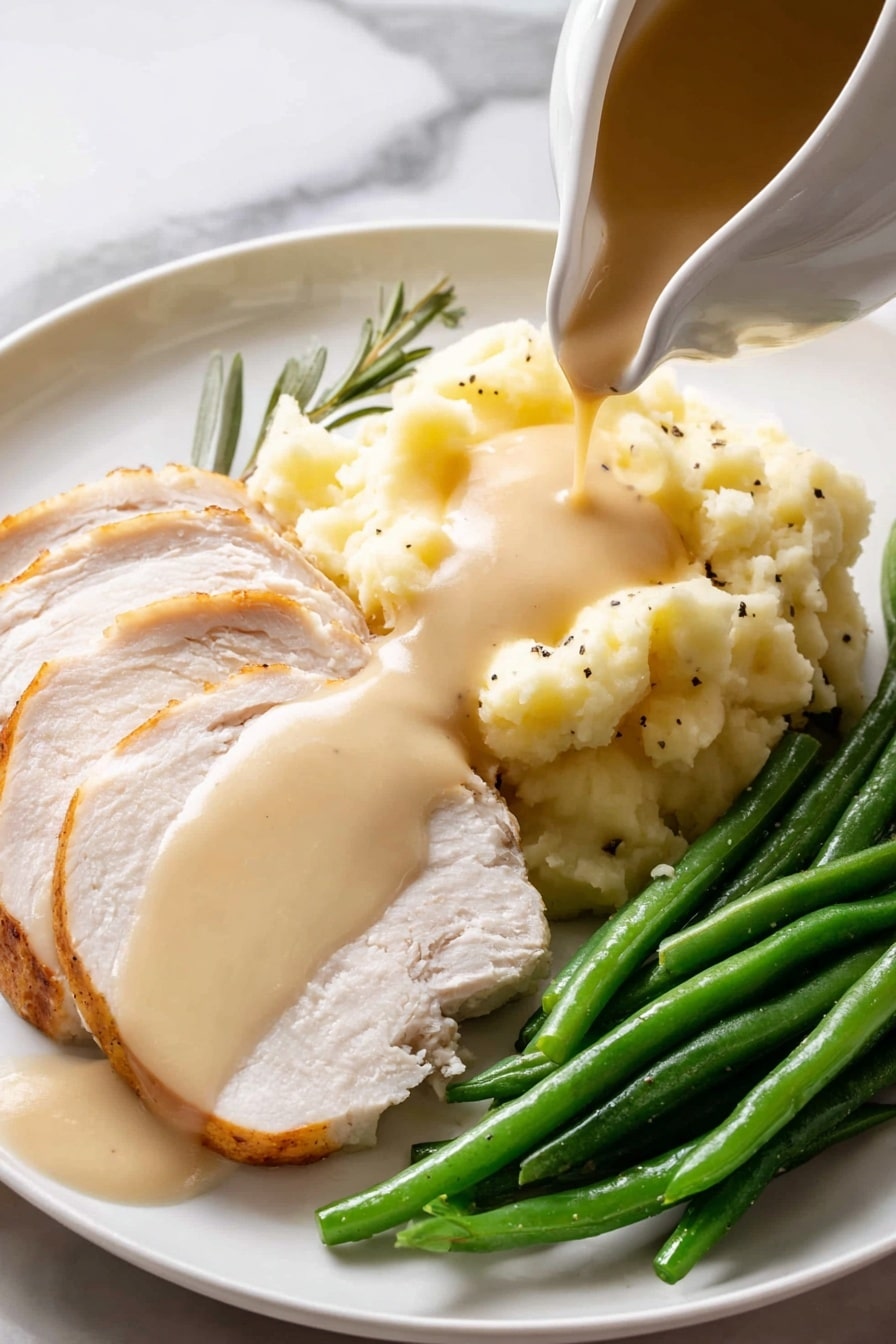 A white gravy boat filled with light brown smooth sauce, speckled with black pepper, sits on a round white speckled plate with a brown rim. Two fresh green herb sprigs, one rosemary and one sage leaf, rest beside the gravy boat on the plate. A shiny silver spoon lies on the plate next to the gravy boat, and the entire setting is placed on a white marbled surface. photo taken with an iphone --ar 2:3 --v 7 - Easy Turkey Gravy From Drippings, homemade turkey gravy, Thanksgiving turkey gravy, savory turkey gravy recipe, how to make turkey gravy from drippings