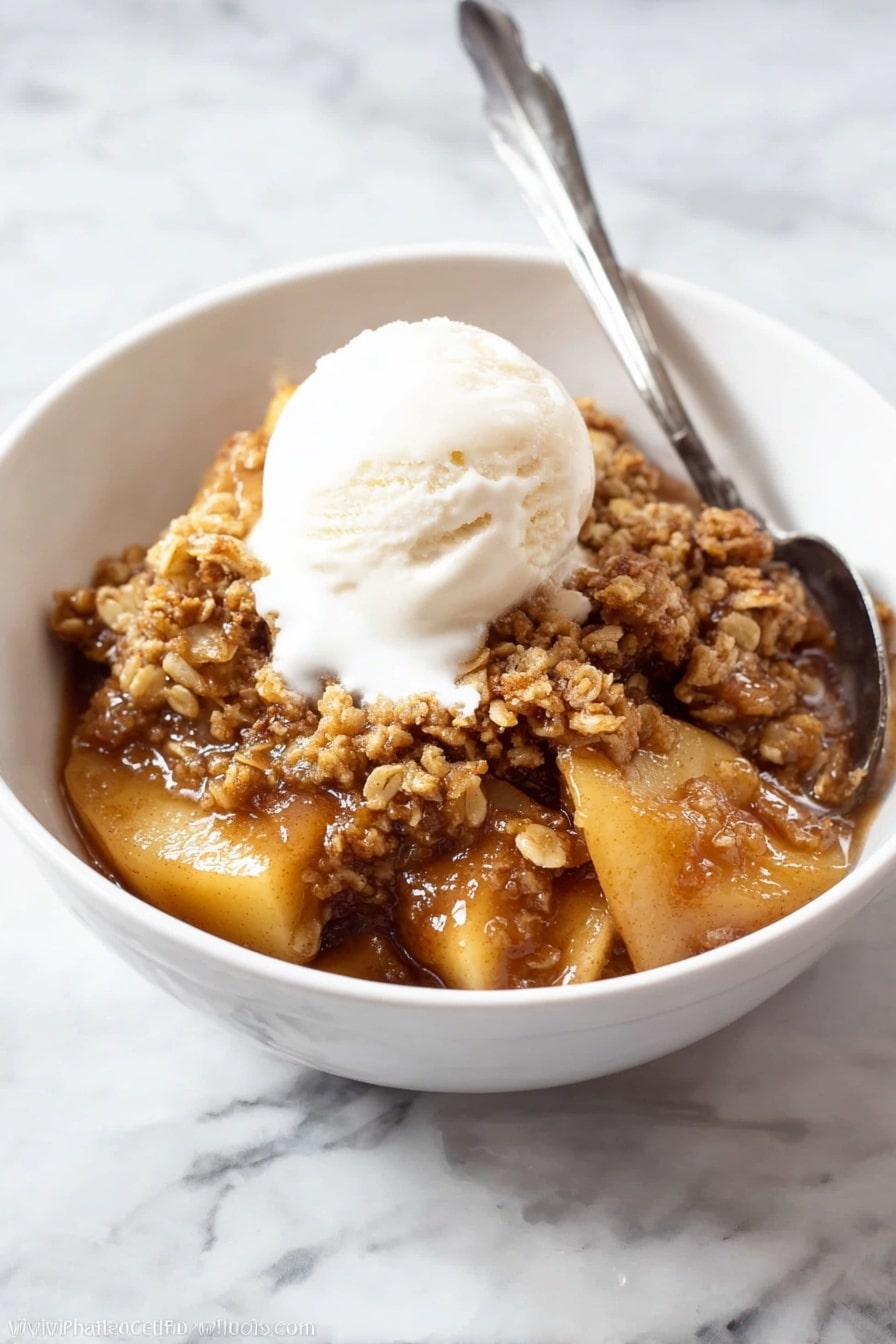 The image shows a white oval dish filled with a warm, brown dessert that has two main layers. The bottom layer is soft, cooked apple slices with a shiny, caramel-like sauce that looks sticky and rich. The top layer is a crumbly, golden brown oat and nut topping that covers the apples in uneven chunks. A silver spoon is dipped into the right side of the dish, slightly disturbing the topping and revealing more of the apple filling underneath. The dish is placed on a white marbled surface, making the warm colors of the dessert stand out. photo taken with an iphone --ar 2:3 --v 7 - Apple Crisp, Apple Crisp dessert, Fall dessert recipes, homemade apple crisp, best apple crisp recipe