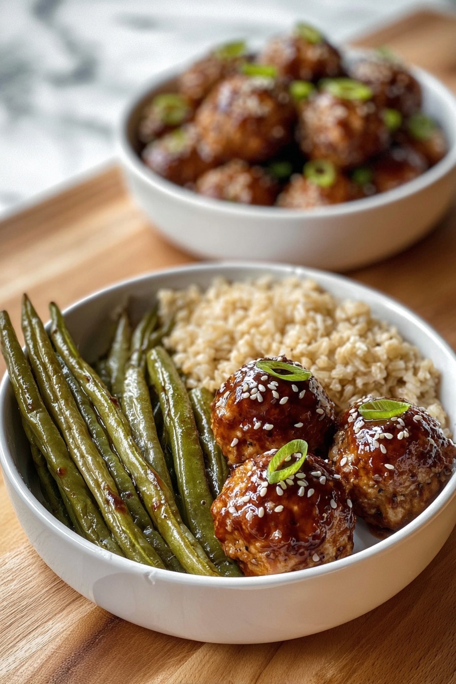 A white bowl contains three sections of food: on the left, a group of long, green roasted green beans with a slightly wrinkled texture; next to them at the bottom, a serving of light brown cooked rice with a soft, grainy look; on the right side, three round golden-brown meatballs covered with a shiny dark brown glaze, sprinkled with white sesame seeds and small green onion pieces on top. Behind this bowl, there is another white bowl filled with similar glazed meatballs, slightly blurred. Both bowls rest on a wooden surface with a white marbled texture background. Photo taken with an iphone --ar 2:3 --v 7 - Asian Glazed Turkey Meatballs, turkey meatballs with Asian glaze, healthy turkey meatball recipe, quick Asian meatball dinner, flavorful turkey meatballs