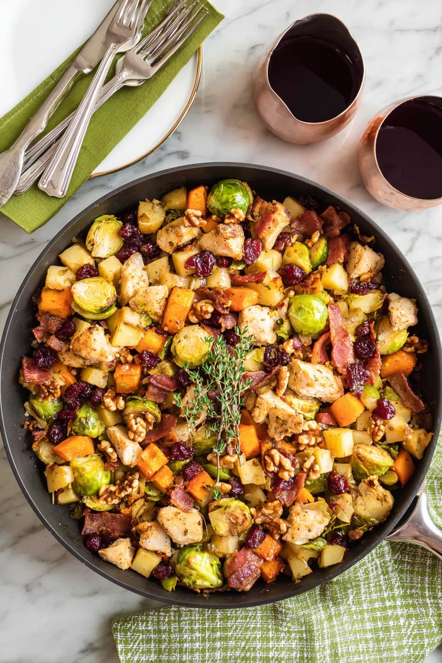 A large black pan filled with a colorful mix of cooked ingredients sits on a white marbled surface with a green cloth and fork on the left. The mix has three main layers: a base of cubed orange sweet potatoes, light yellow apple pieces, and halved green Brussels sprouts; a middle layer of beige chicken pieces and crispy, dark brown bacon bits; and a top layer of whole walnuts and dried dark red cranberries. A small sprig of fresh green thyme rests on top, and a wooden spoon leans inside the pan from the right side. Two glasses filled with dark red wine are placed nearby on the white marbled surface, with one glass partially reflected on a shiny black bowl. photo taken with an iphone --ar 2:3 --v 7 - One-Pot Easy Harvest Chicken Skillet, easy fall dinner ideas, quick weeknight chicken recipes, cozy skillet meals, healthy harvest chicken dish