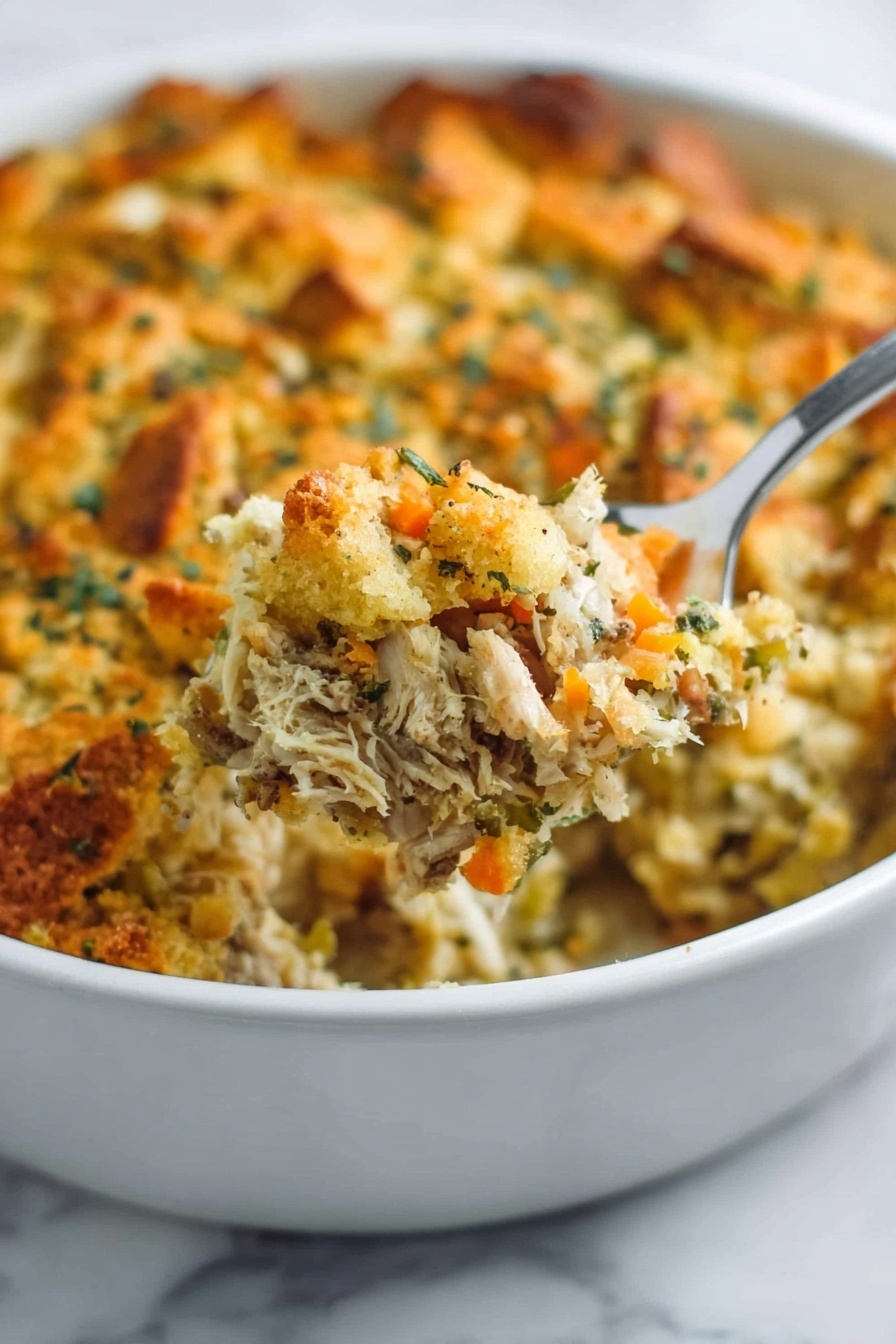 This image shows a white oval baking dish filled with a layered casserole topped with golden brown toasted bread cubes sprinkled with chopped green herbs. The top layer is crunchy and slightly uneven, covering a creamy mixture below that has visible bits of mushrooms and herbs. A wooden spoon scoops some casserole from the dish, revealing the creamy, textured filling beneath the toasted top. The dish is set on a white marbled surface, with a woman's hand holding the edge of the dish on one side. photo taken with an iphone --ar 2:3 --v 7 - Creamy Chicken Wild Rice Casserole, hearty chicken rice bake, easy comfort food recipes, wholesome casserole dinner, one-dish chicken rice casserole