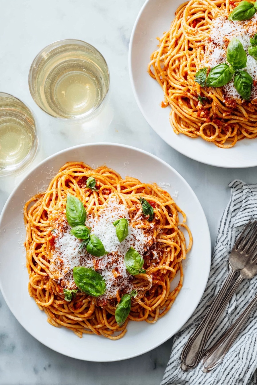 Two white plates with round shapes, each holding a serving of spaghetti layered with red tomato sauce, topped with a layer of white grated cheese and scattered green basil leaves. The spaghetti is twisted into small nests that fill most of the plate. Near the plates are two forks resting on a white and blue striped cloth napkin, and two almost full glasses of white wine are seen in the top left corner. Everything is set on a white marbled table surface. photo taken with an iphone --ar 2:3 --v 7 - Easy Tomato Pasta Pomodoro, Tomato Pasta with Basil and Garlic, Simple Italian Pasta Recipe, Quick Homemade Tomato Pasta, Classic Pasta Pomodoro