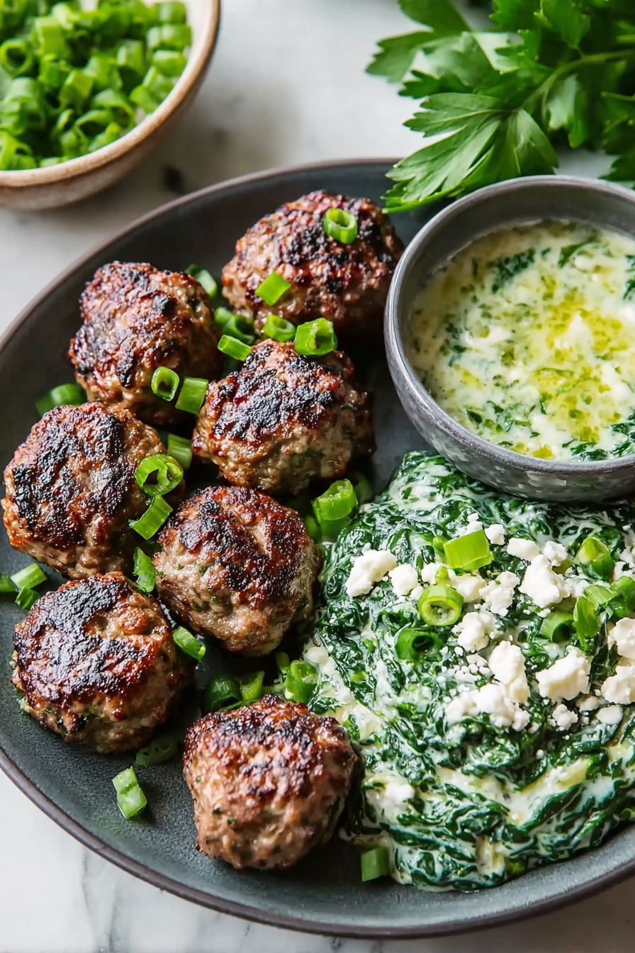 The image shows a dark gray plate with seven browned meatballs placed on the left side. On the right side of the plate, there is a creamy spinach mixture topped with chopped green onions and small white crumbles, likely cheese. Behind the plate, there is a small gray bowl filled with a greenish sauce that includes white chunks. Fresh green parsley leaves are visible in the background. The surface under the plate is a white marbled texture. photo taken with an iphone --ar 2:3 --v 7 - Spicy Lamb Meatballs with Green Herb Dip, spicy lamb meatballs recipe, flavorful lamb meatballs, easy lamb meatball appetizer, herb dip for lamb balls