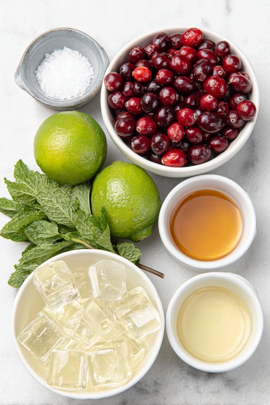 Flat lay of fresh green lime wedges, whole bright red cranberries, a few sprigs of vibrant fresh mint leaves, coarse crystals of salt in a small white ceramic bowl, clear ice cubes arranged neatly, and small white ceramic bowls each filled with pale golden tequila blanco, clear triple sec, fresh pale green lime juice, deep red cranberry juice, and light amber simple syrup, all ingredients naturally fresh and arranged in perfect symmetry on a clean white marble surface, soft natural light, photo taken with an iPhone, professional food photography style, fresh ingredients, white ceramic bowls, no bottles, no duplicates, no utensils, no packaging --ar 2:3 --v 7 --p m7354615311229779997 - Christmas Mistletoe Margarita, festive margarita ideas, holiday cocktail recipes, Christmas drinks with cranberry, easy holiday margarita