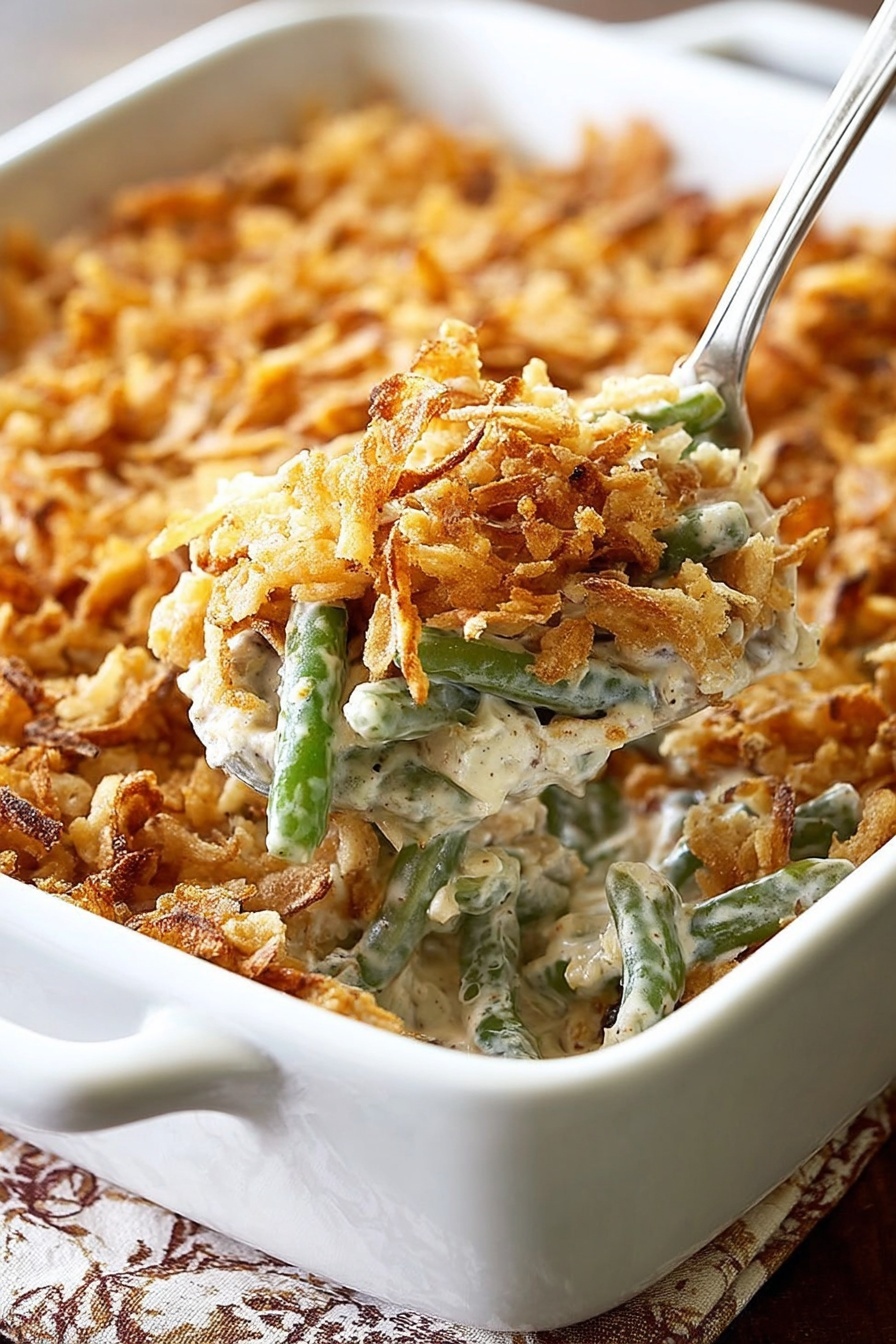 A white rectangular baking dish filled with a creamy green bean casserole topped with a thick layer of crispy golden brown fried onions. The casserole shows soft green beans mixed with a light beige creamy sauce beneath the crunchy topping. In the foreground, a white spoon lifts a serving, revealing the creamy texture mixed with green beans and bits of fried onions. The dish is placed on a table with a white marbled texture showing under the edges. Photo taken with an iphone --ar 2:3 --v 7 - Perfect Green Bean Casserole with Bacon, green bean casserole with bacon, easy green bean casserole, cheesy green bean casserole, holiday green bean side dish